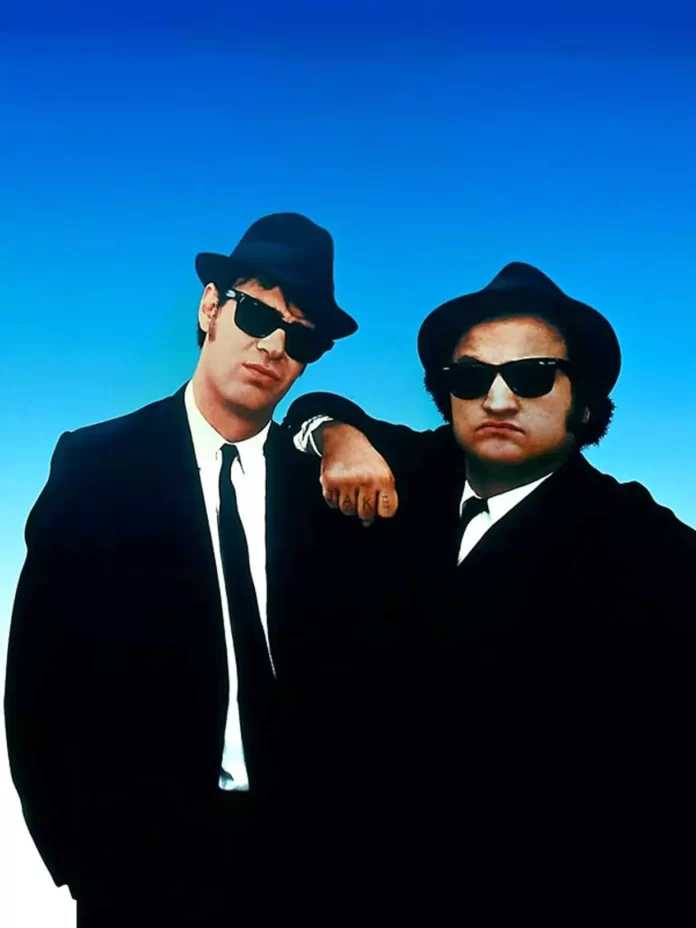Two-men-in-black-with-glasses-and-hat-blue-screen