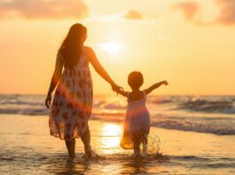 woman-with-her-child-walking-on-the-sunset-shore