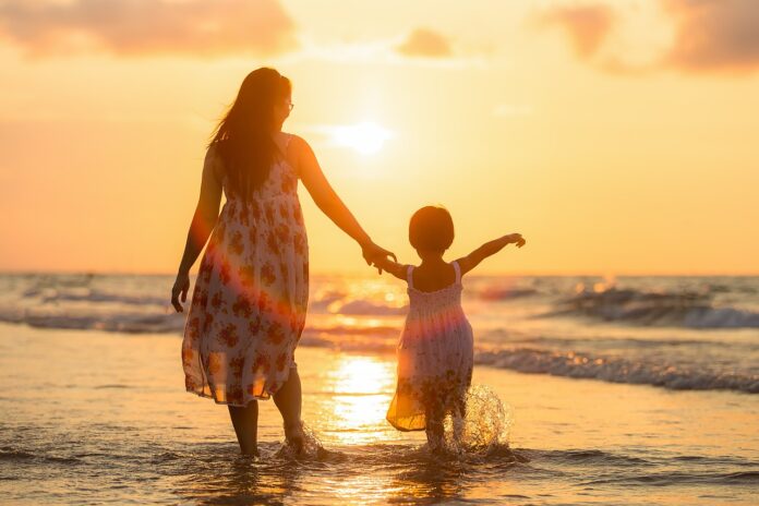 woman-with-her-child-walking-on-the-sunset-shore