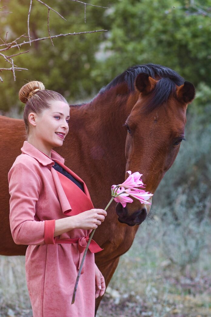 pink-dressed-woman-with-a-flower-and-next-to-a-horse