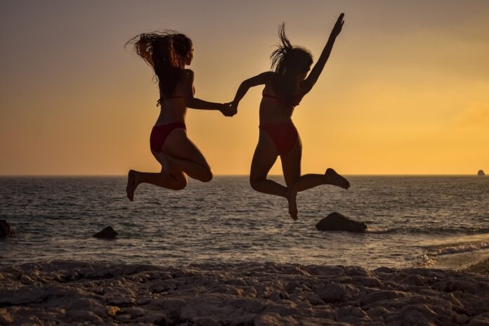 two-girls-jumping-on-the-beach-at-the-sunset