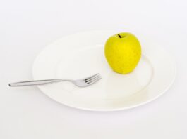 an-apple-on-a-plate-with-a-fork