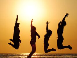 jumping-young-people-with-the-sunset-behind-on-a-golden-beach