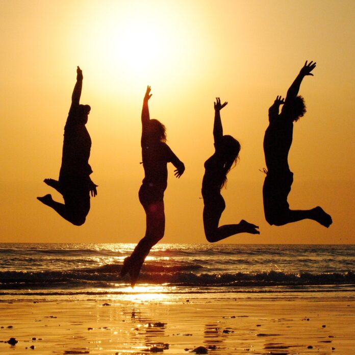 jumping-young-people-with-the-sunset-behind-on-a-golden-beach